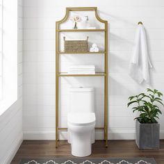 a white toilet sitting in a bathroom next to a shelf with towels and potted plants