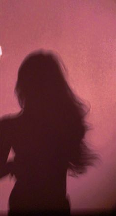 a blurry photo of a woman's long hair in front of a pink wall