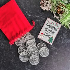 christmas activity coins are sitting next to a red drawstring bag and pine cones