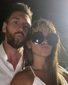 the man and woman are posing together for a photo in front of some bright lights