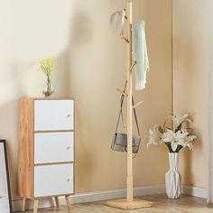 a coat rack in the corner of a room next to a vase with flowers on it