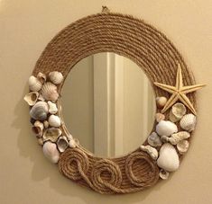 a rope wreath with seashells and starfish hangs on the wall next to a mirror