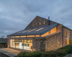 a stone building with glass windows on the top floor and an open patio area in front of it