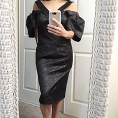 a woman taking a selfie in front of a mirror wearing a black dress and holding a cell phone