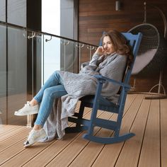 a woman sitting in a rocking chair talking on the phone