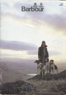 a man standing on top of a hill with two dogs next to him and another dog behind him