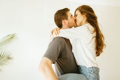 a man and woman kissing each other in front of a plant