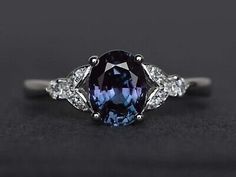 an oval cut blue and white sapphire ring with three diamonds on the sides, set in 18k white gold