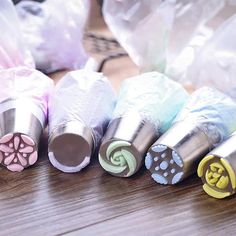 several different colored spools of thread on a wooden table with plastic bags in the background