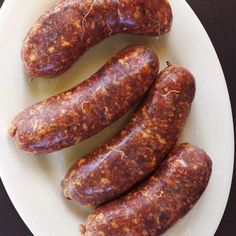 three sausages on a white plate sitting on a table