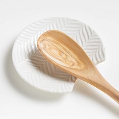 two white plates with wooden spoons sitting on top of each other in front of a white background