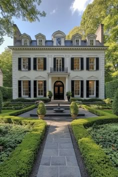 a large white house surrounded by hedges and trees