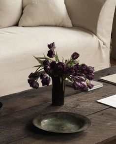 a vase with purple flowers sitting on a coffee table