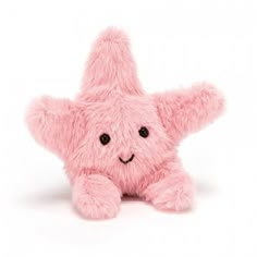 a pink teddy bear with black eyes and a star shaped nose sitting on the ground