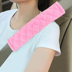 a woman sitting in the back seat of a car with a pink arm pad on it