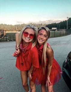 two girls in red dresses and sunglasses posing for the camera with their arms around each other