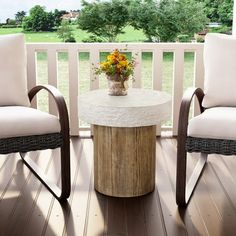 two chairs and a table on a deck with flowers in vases sitting on the table