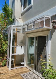 an outside view of a house with a cat in the door and some plants on the deck