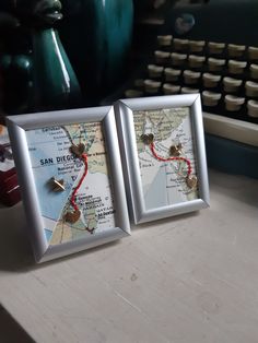 two framed maps are sitting on a desk next to an old typewriter and keyboard