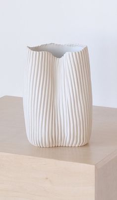 a white vase sitting on top of a wooden table