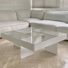 a white couch sitting next to a glass table on top of a hard wood floor