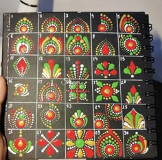 a hand holding a notebook with designs on it