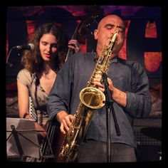 a man playing a saxophone on stage next to a woman