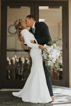 a bride and groom kissing in front of an entrance