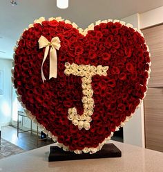 a large heart shaped arrangement with roses in the shape of a cross and letter t