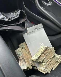 a pile of money sitting in the back seat of a car next to a wallet