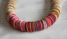 a close up of a colorful necklace on a piece of paper with writing in the background