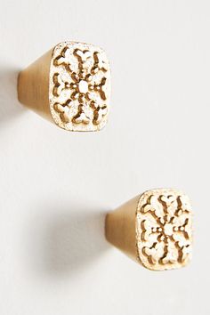 two pairs of gold colored earrings on white background, one has an intricate design in the middle