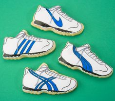 four decorated cookies with white and blue running shoes on green background, ready to be eaten