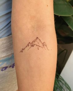 a small mountain tattoo on the arm