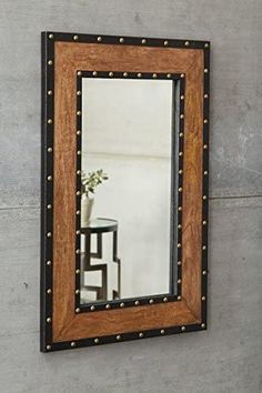 a mirror hanging on the wall next to a table with a vase and flower in it