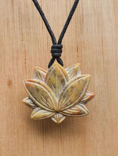 a wooden table with a black cord on it and a pendant that has a flower in the center