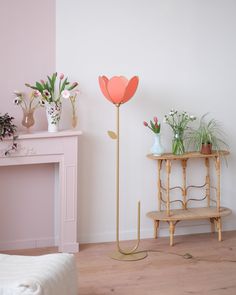 a living room with pink walls and flowers in vases next to a gold stand