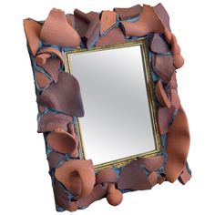 a mirror that has been made out of clay and is broken in half to reveal the frame