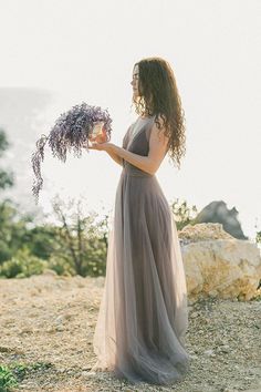 a woman in a long dress holding flowers