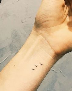 a person's arm with a small bird tattoo on the left side of their wrist