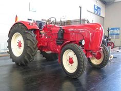 an old red tractor parked in a garage