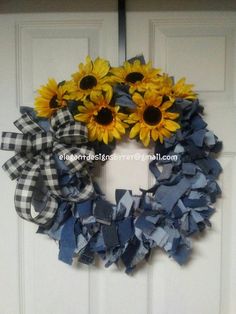 a wreath with sunflowers and blue ribbon hanging on the front door to welcome guests