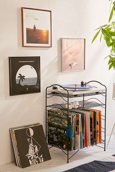 there is a metal rack with books on it in the corner next to some pictures