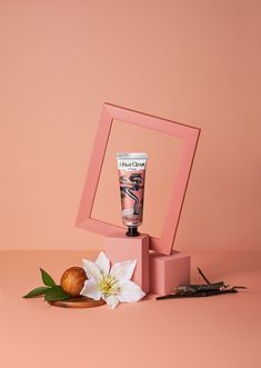 a pink box with a tube of hand cream next to it and a flower on the table