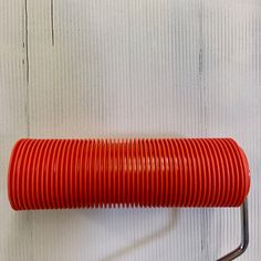 a red hose is hanging on the wall next to a metal rack with two handles