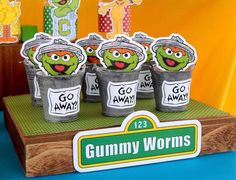 the gummy worms cupcakes are sitting on top of a wooden tray with stickers