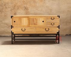 a wooden dresser sitting on top of a metal frame next to a wall with a cement floor