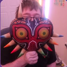 a man holding up a mask with spikes on it