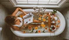 a woman laying in a bathtub filled with orange slices