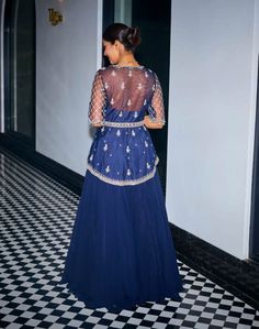 Embrace exquisite elegance in this midnight blue hand-embroidered asymmetric peplum ensemble! Intricately adorned with sequins, stones, and beads, this peplum exudes opulence and charm. The v-neckline and handmade tassels at the sleeves add a touch of sophistication. Paired with a flowy georgette skirt and a matching net dupatta, this ensemble offers a perfect blend of grace and allure. Fitted Embellished Peplum Lehenga, Fitted Embellished Lehenga With Peplum Design, Traditional Embellished Peplum Dress, Elegant Fitted Peplum Lehenga, Blue Embellished Georgette Sets, Anarkali Embellished Peplum Sets, Festive Embellished Royal Blue Sets, Anarkali Sets With Embellished Peplum, Blue Sequined Party Wear Sets